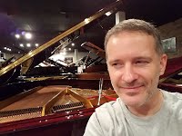 Chad Mitchell surrounded by pianos at Stilwell Pianos